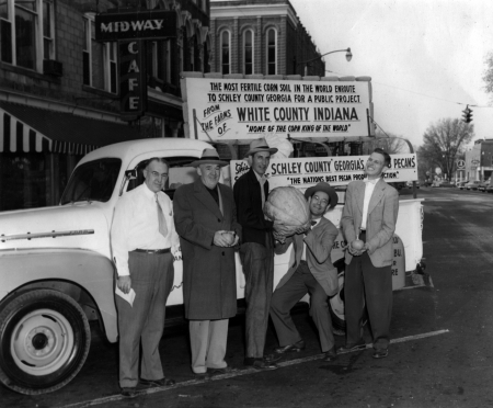 Richard (Dick) Rainbolt squatting to hold a giant prize pumpkin in Delphi, IN in 1954.