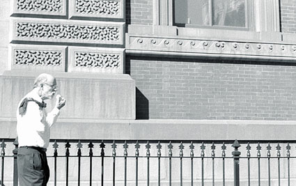 A businessman walking along a street in Washington, DC eating an apple.