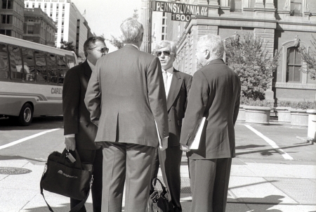 A small gaggle of businessmen congregating on a Washington DC street corner.