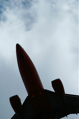 The silloute of a plane matched against clouds in the sky.