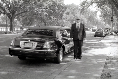 A photography of a driver next to his limo on Constitution Avenue in Washington, D.C.