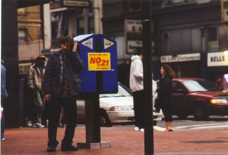 A man leaning against a pay phone in San Francisco