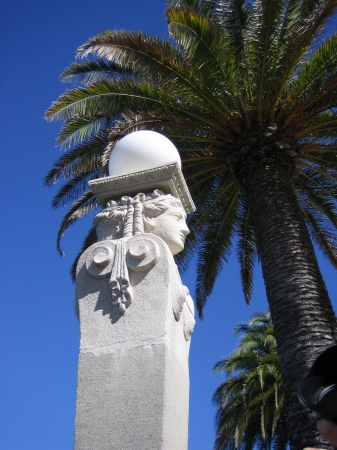 A limestone Roman sculpture and palm trees at Hearst Castle, CA.