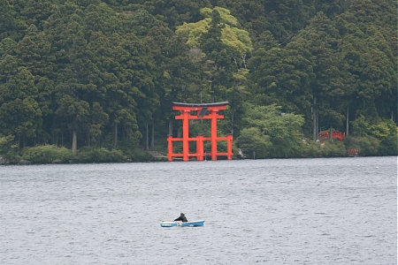 A photograph of a man rowing on Lake Ashi in Japan.