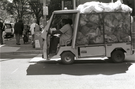 A view of a small truck hauling garbage bags away from a hotel near the GW University.