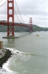 A western view of the Golden Gate Bridge with surfers below.